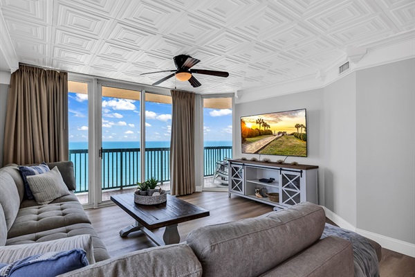 High-rise oceanfront balcony with seating, overlooking beach, RV park, and blue ocean horizon