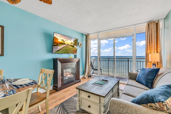 Beachfront condo living room with turquoise walls, fireplace, ocean view balcony, and modern furnishings